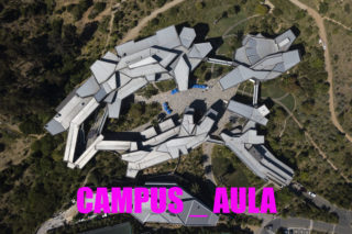 Aerial view of grey and white building within a green landscape