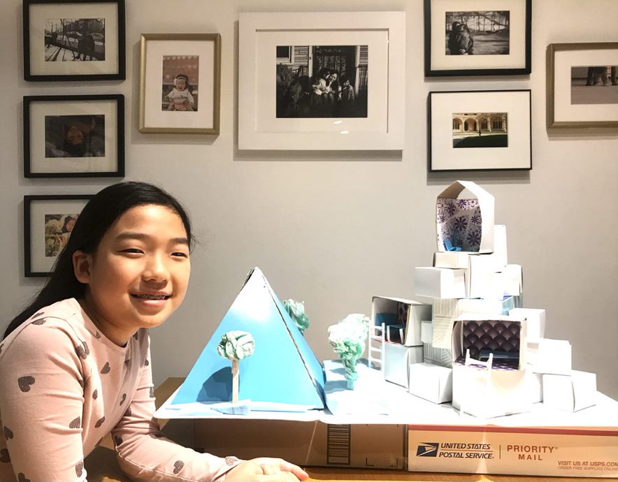 Child posing with pyramid and building model