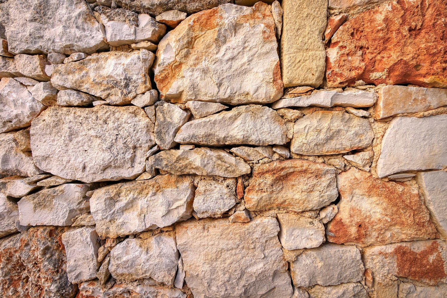 Photo of natural stone wall structure with stones made of random size and texture