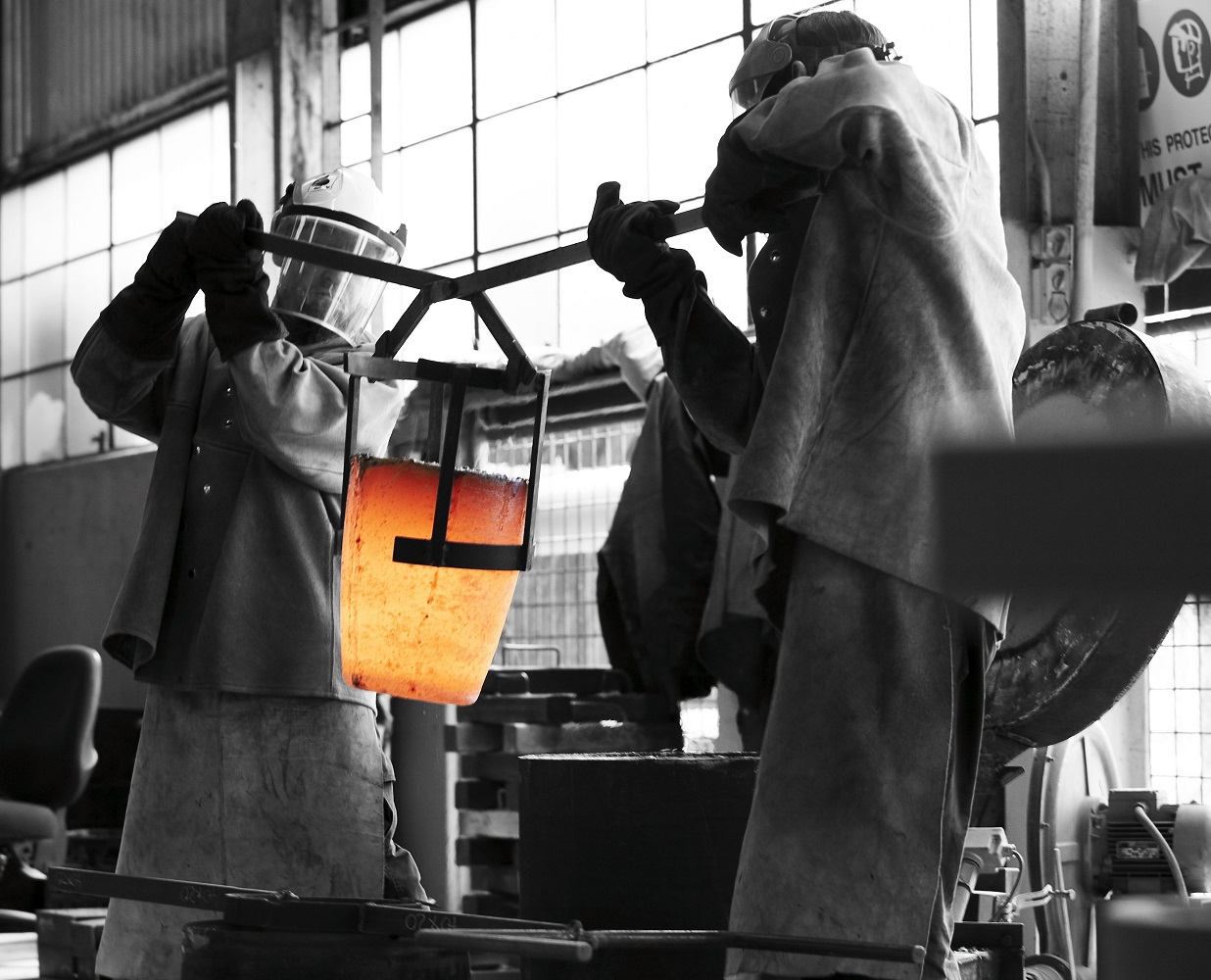 This is an image of two metal workers holding a hot crucible.