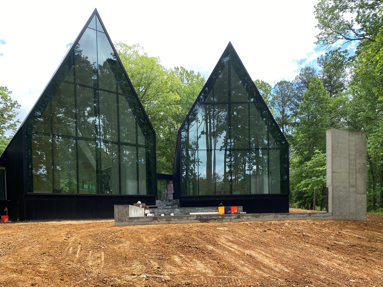 Daylight photograph of the Steeplechase House highlighting it's high pitch A-frame facade made of glass.