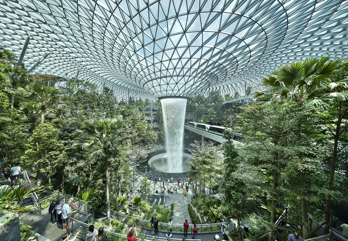 Interior photo of Jewel Changi Airport showcasing an indoor rainforest with a large waterfall in the center