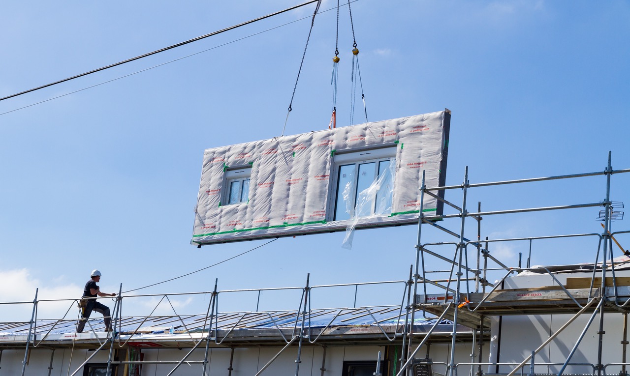 Building wall component being lifted into place on a building exterior