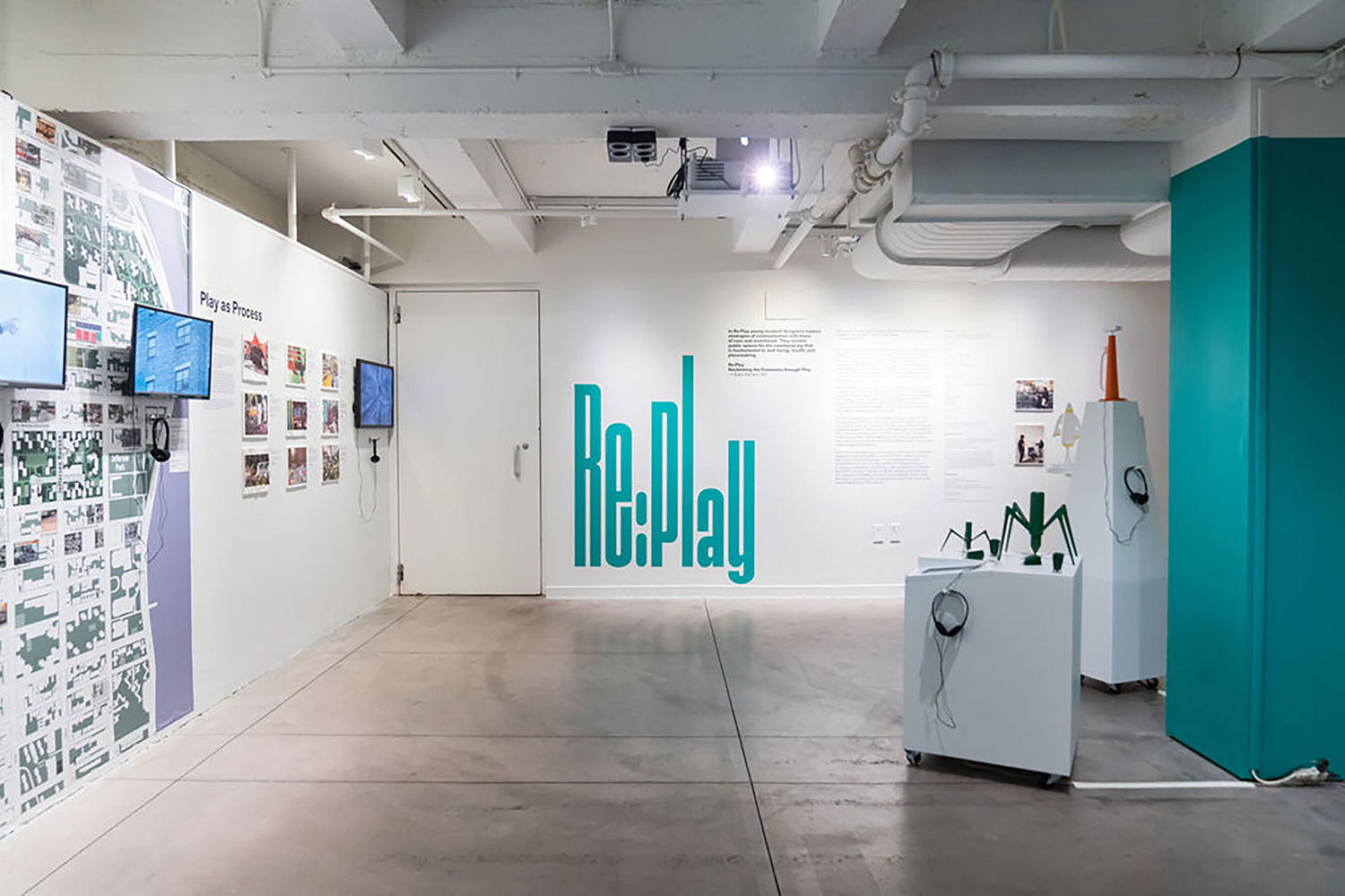 Installation view with two screens on the left wall and 3D printed models on white square bases on the right