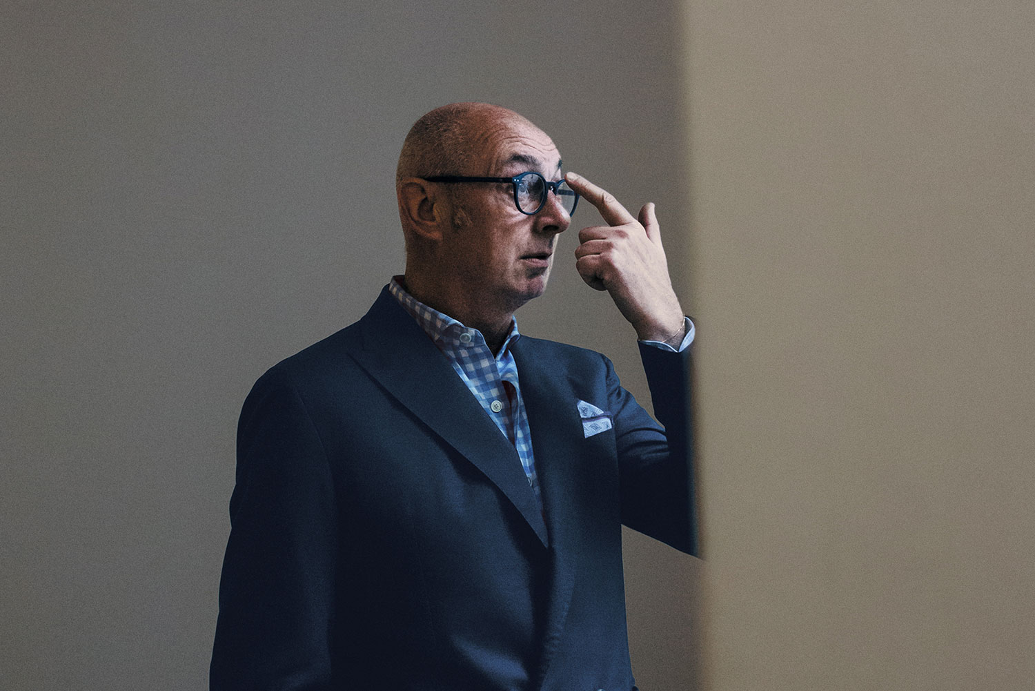 Portrait of Piero Lissoni in a suit and pushing his glasses up on his nose