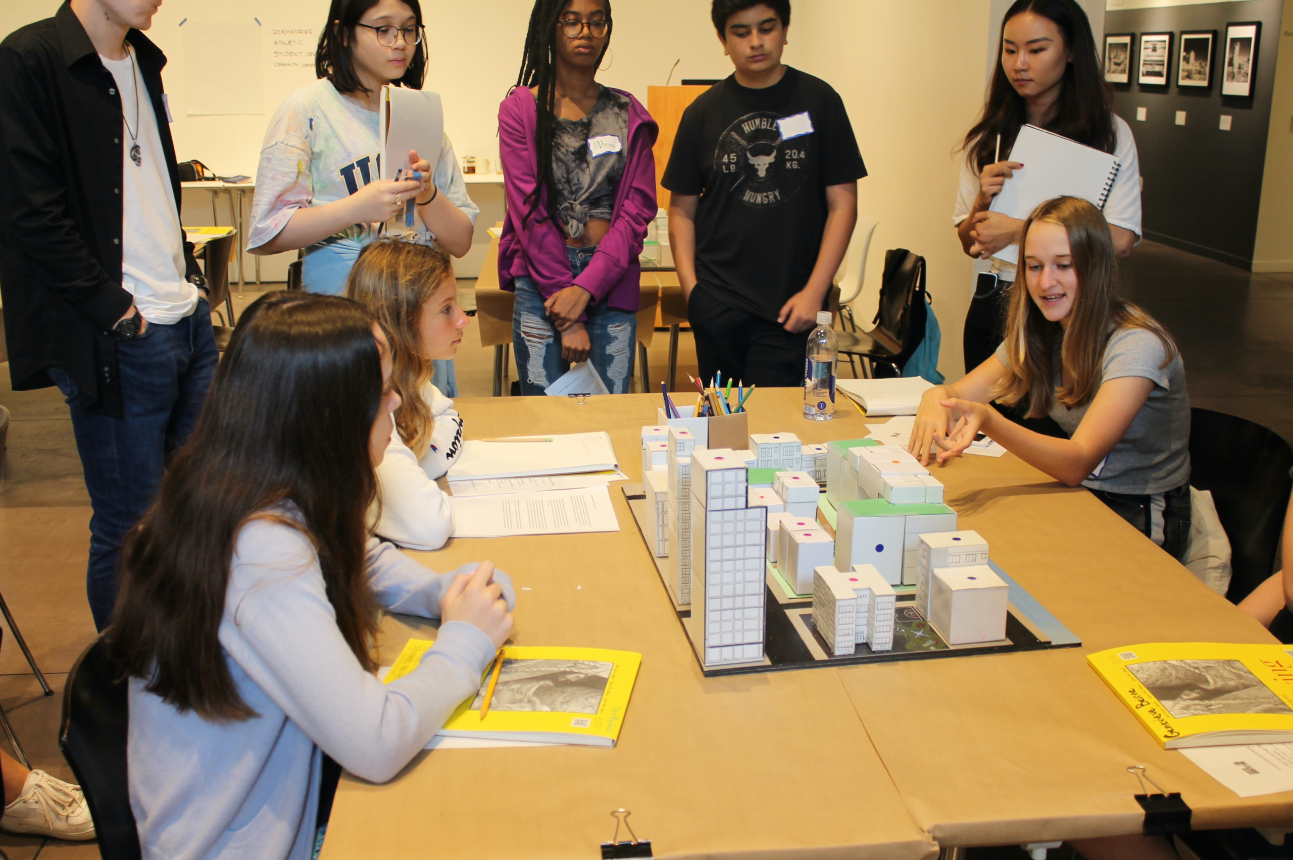 High School Students gathered around a box model of a neighborhood
