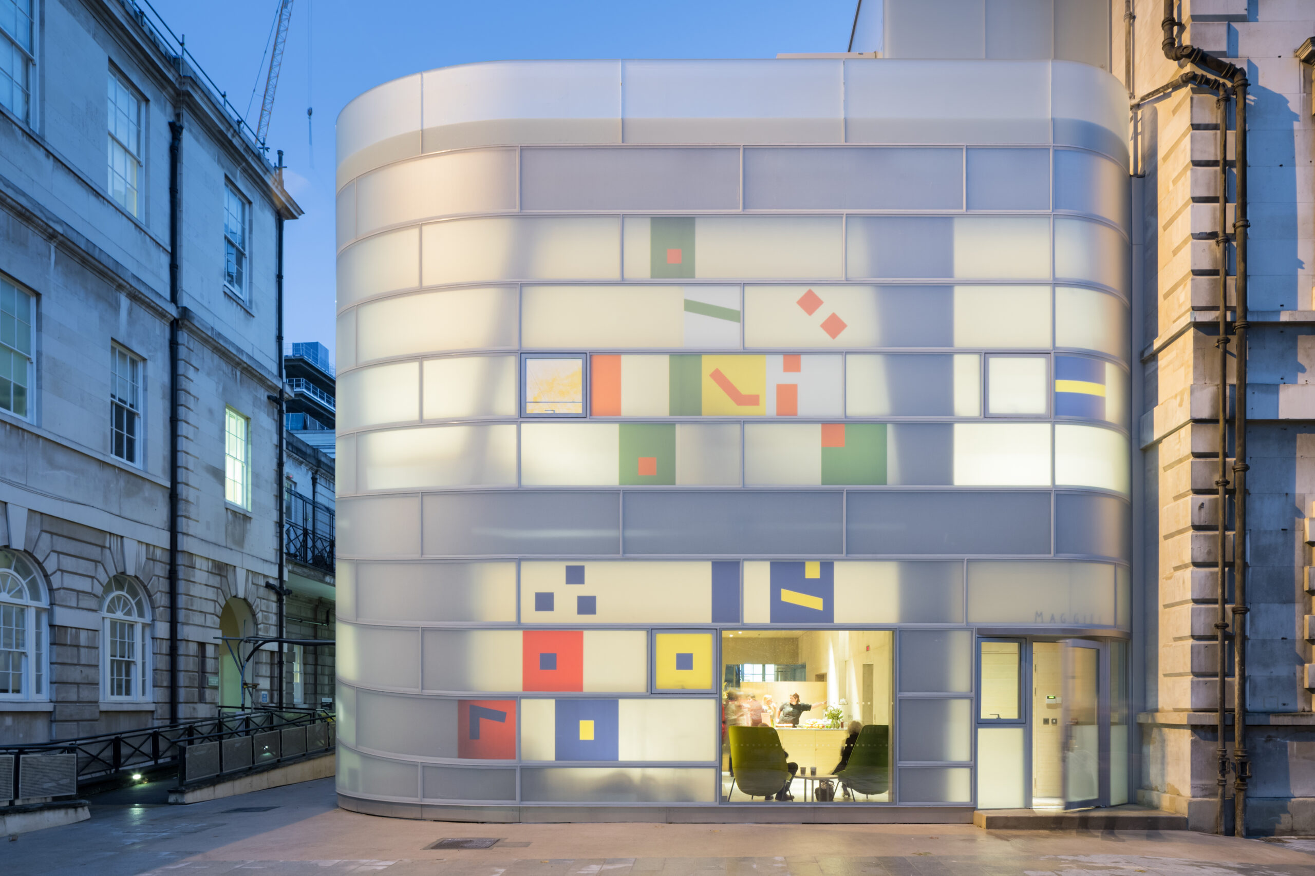 Photo of Steven Holl Architects, Maggie's Centre Barts. The cancer care center’s façade contains colored glass fragments inspired by “neume notation,” a form of Medieval musical notation, connecting to nearby St. Bartholomew’s Hospital and Church of the 12th century.