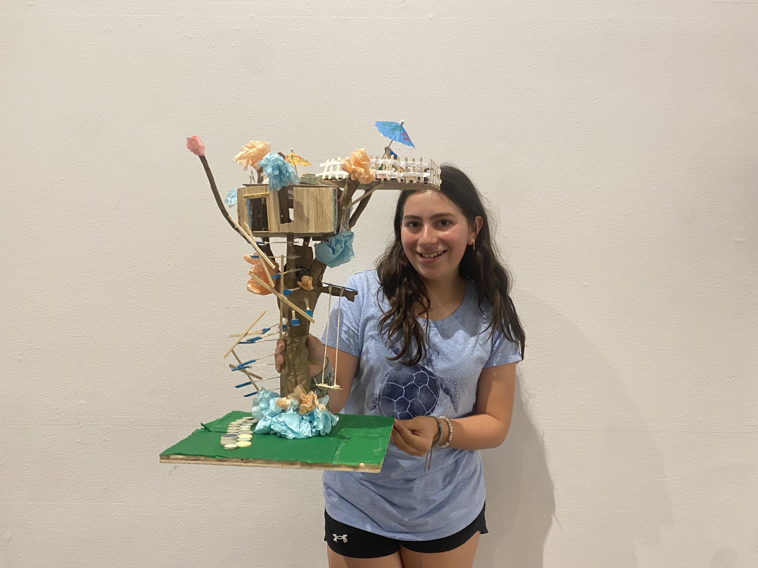 Middle school student holding up her model treehouse