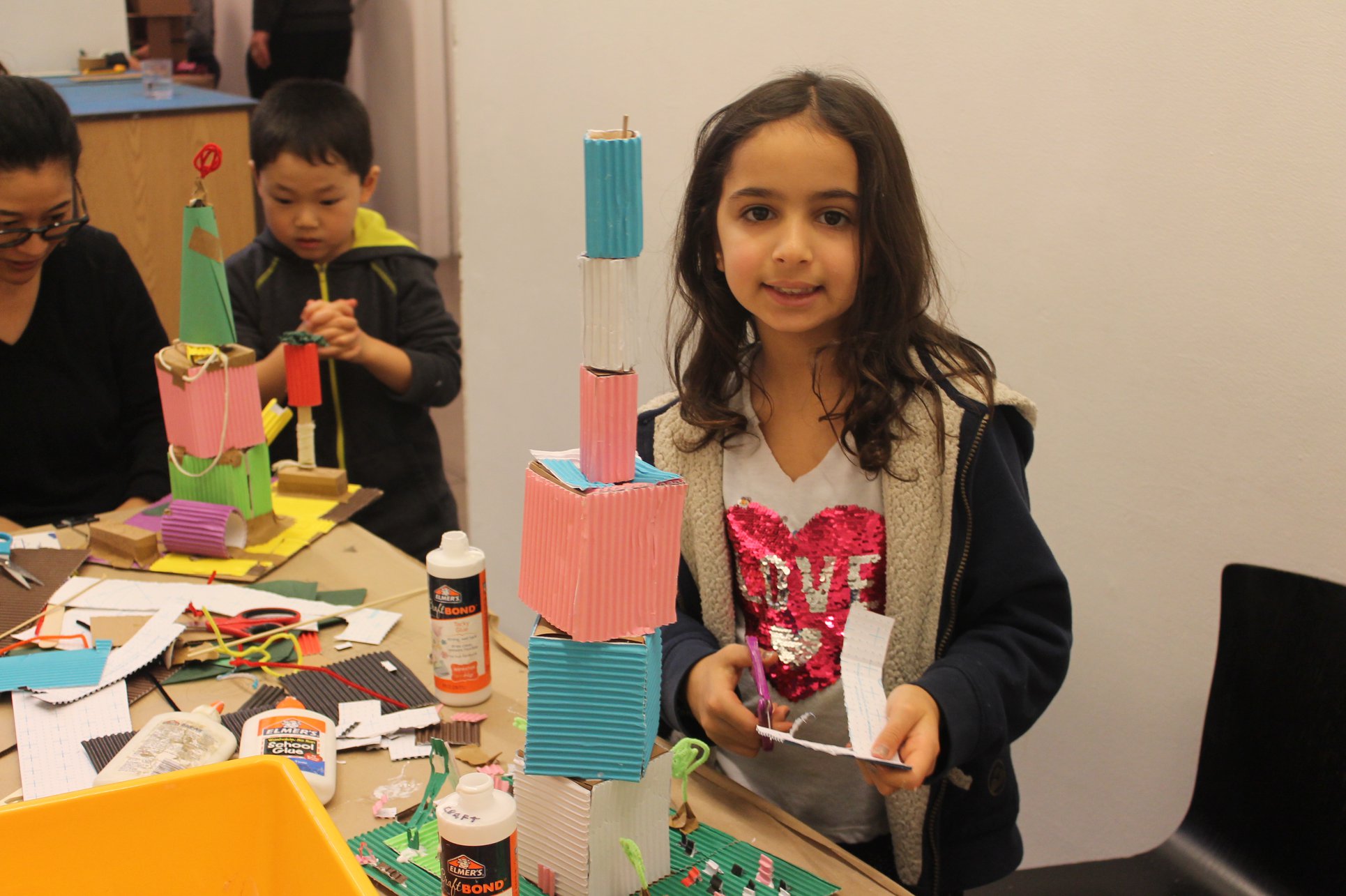 Child standing with their model skyscraper.
