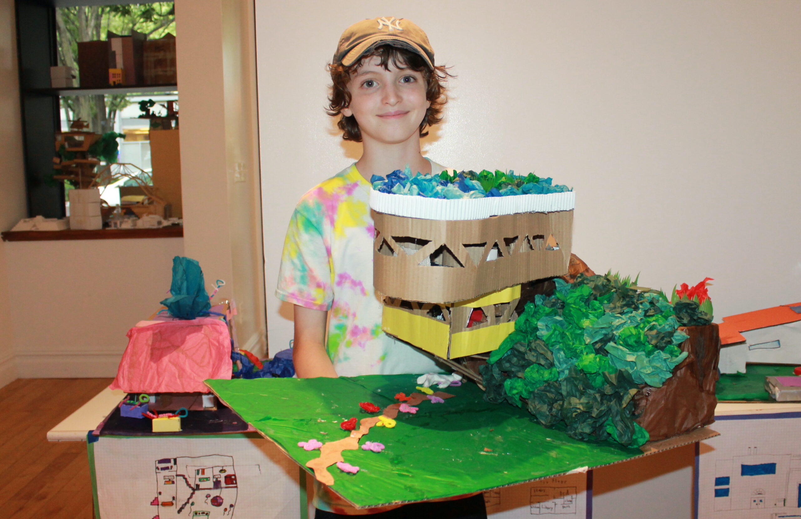 Elementary school student holding their model of a futuristic house on a hill