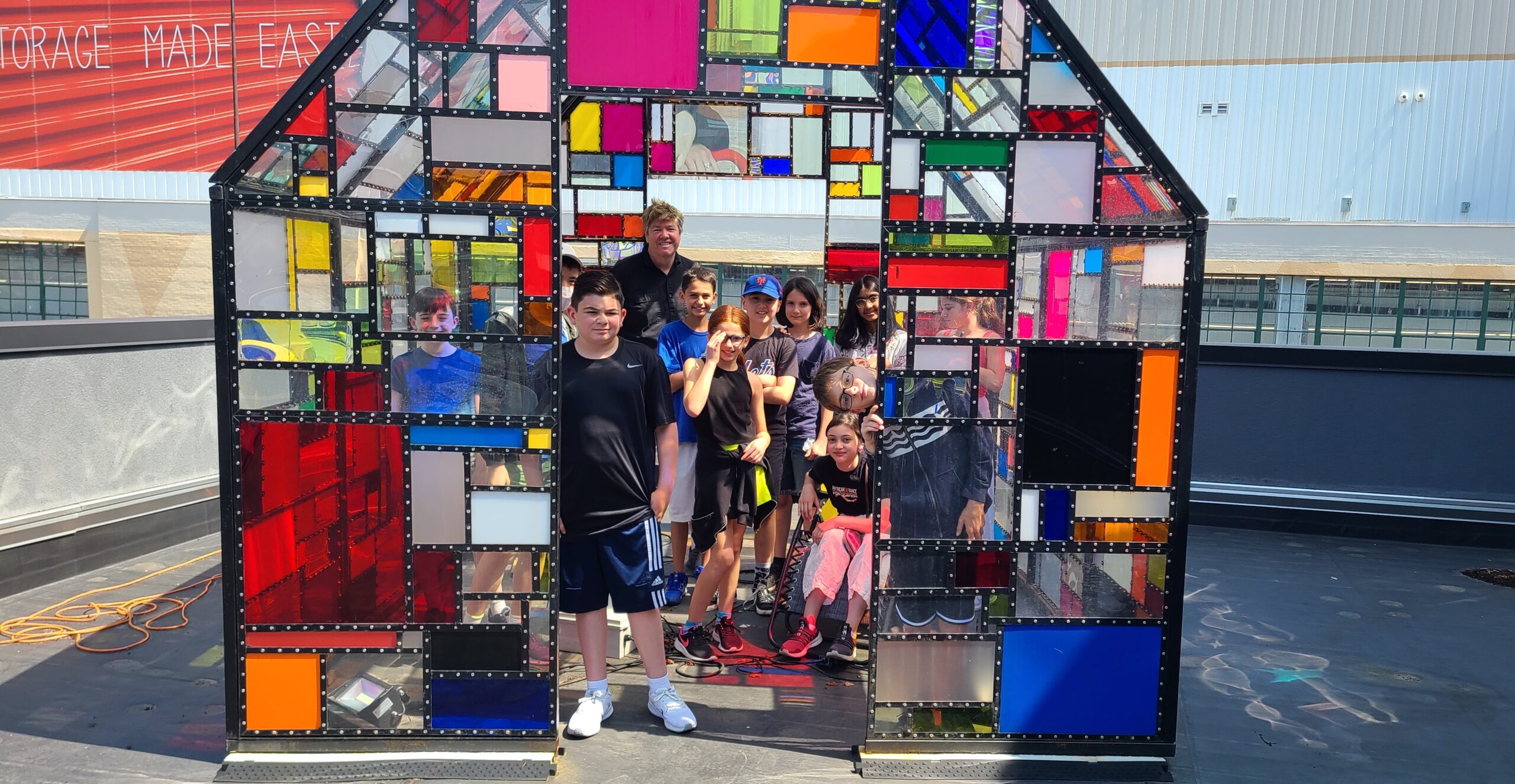 Class of middle school students posing inside a colorful house art installation
