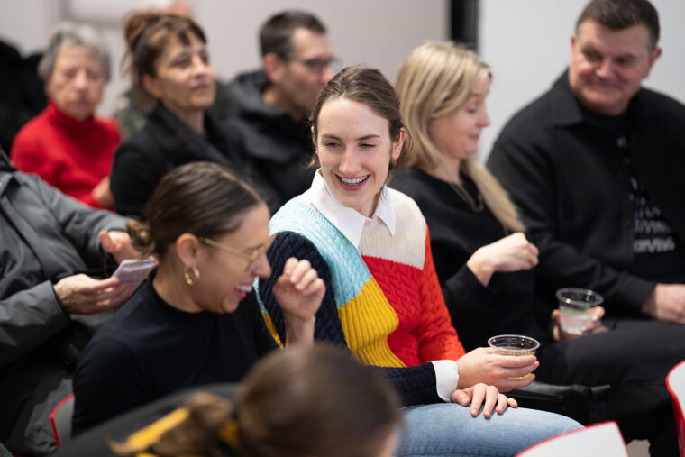 Young adults laughing in audience at new fellows celebration.