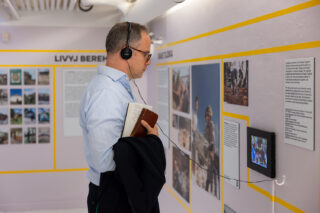 A man wears headphones as he watches a video on the wall of the exhibition.