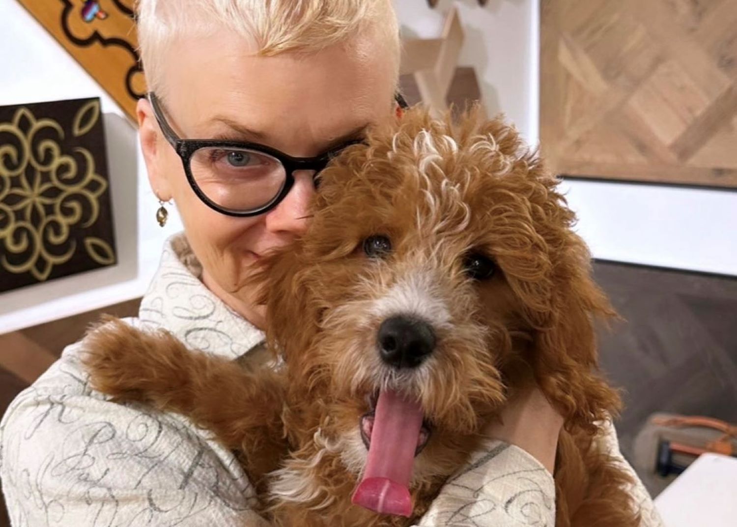 A person looking into the camera while holding a dog.