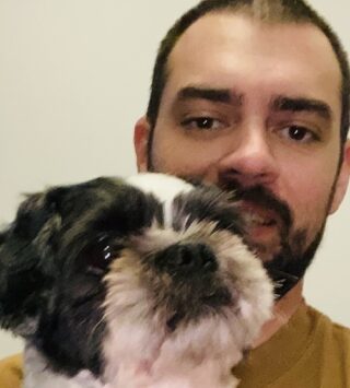 Headshot of Chritopher Gardner holding a black and white dog.