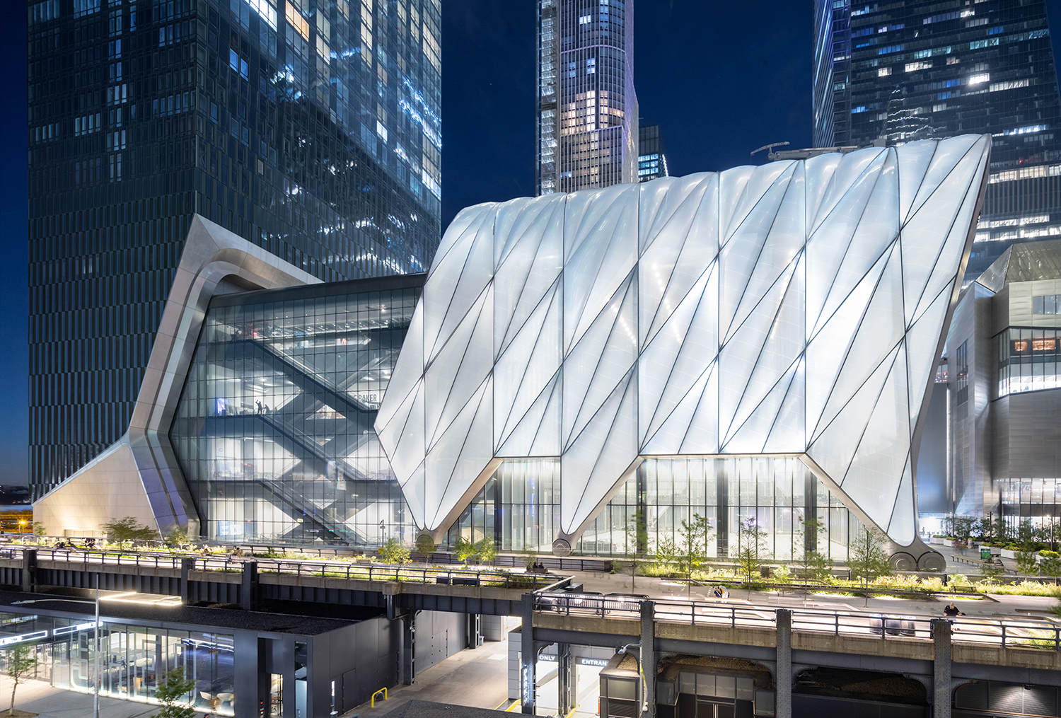 Large multi-story glass enclosed building with pedestrian pathway in front