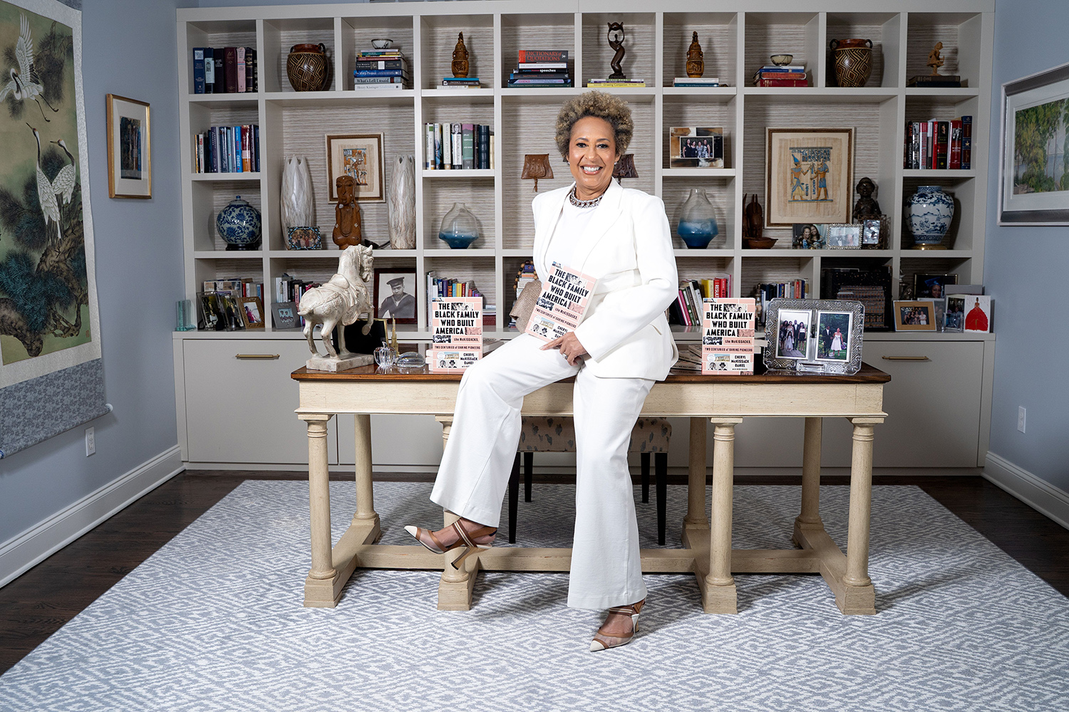 Woman sitting on a desk holding a book in an office