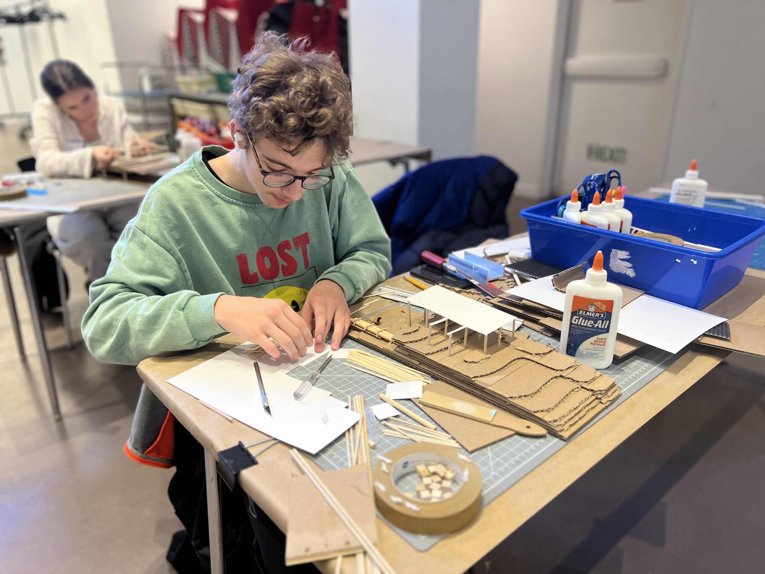 Teen working on cardboard architecture model.