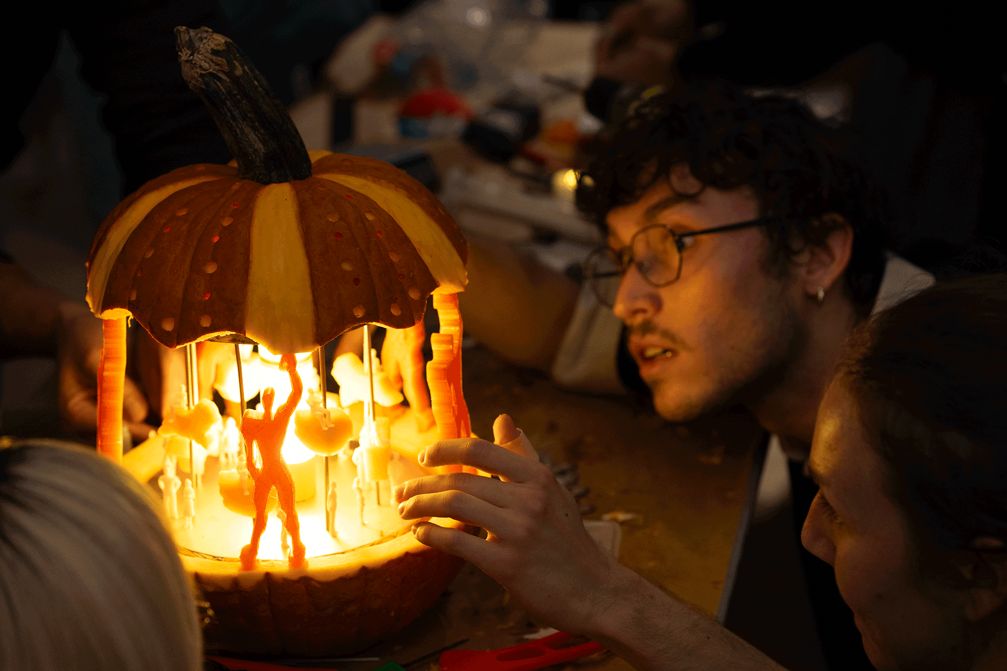 A man peering at a jack-o'-lantern close up